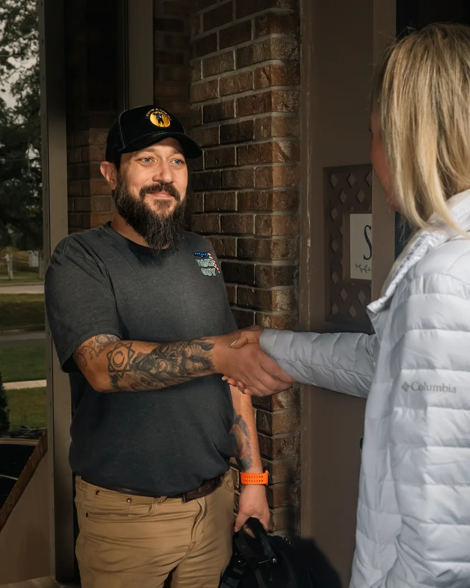 An I Know A Guy AC technician shaking hands with a homeowner at her front door