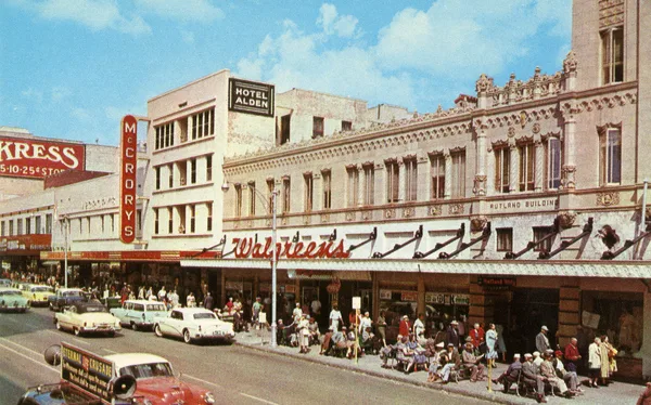 Historic photo of people sitting on the green benches on a downtown St. Petersburg street