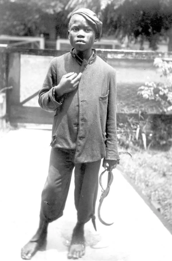 Historic photo of an iceman's helper carrying ice with tongs, 1890s