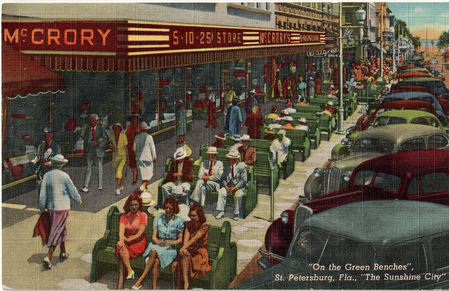 Rows of green benches on the sidewalk outside a McCrory’s five-and-dime, people sitting and strolling, 1940s.