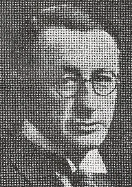 Portrait of a 1920s man in round wire glasses and a suit.