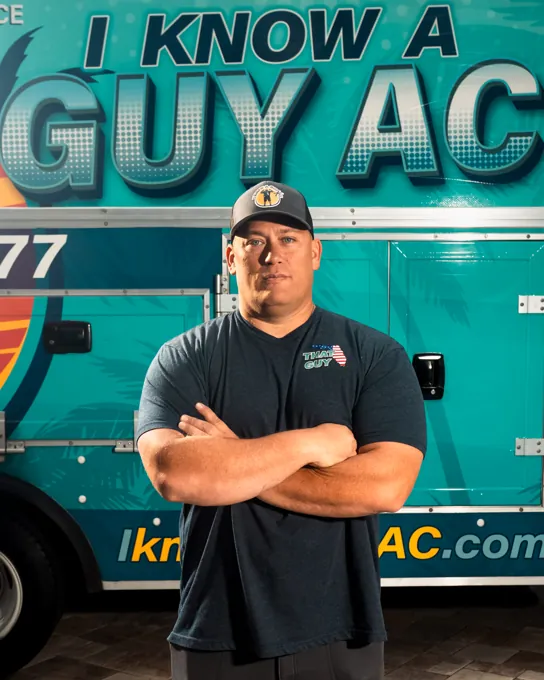 I Know A Guy AC technician standing in front of the branded turquoise truck