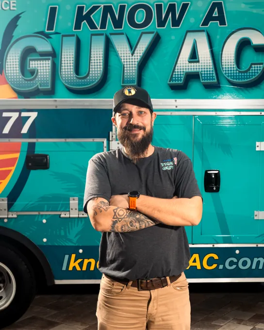 I Know A Guy AC technician standing in front of the branded turquoise truck
