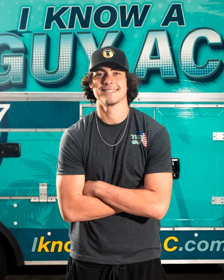 I Know A Guy AC technician standing in front of the branded turquoise truck