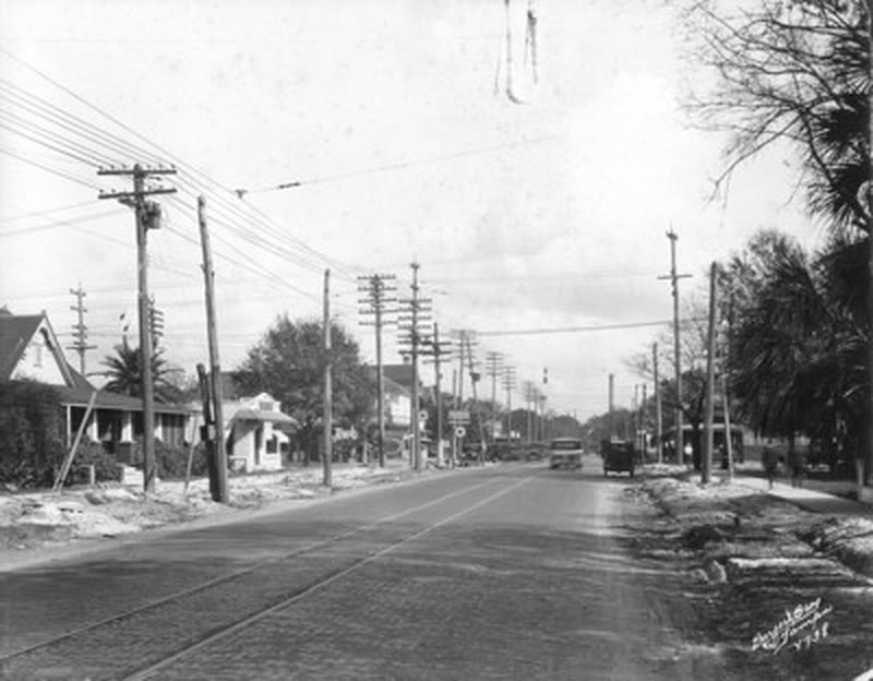 A brick Tampa street with embedded streetcar tracks, power poles, and small frame houses, 1925.